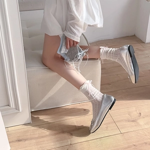Dettaglio di ballerine con fiocco e calze di pizzo con accenti di nastro rosa