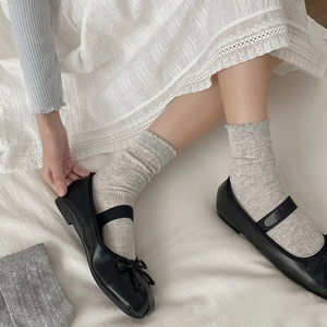 Close-up of grey hollow lace socks with black Mary Jane shoes on white background