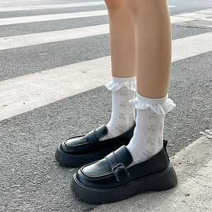 Détail de chaussettes blanches à dentelle et mocassins noirs à semelles épaisses