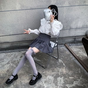 Detail of white over-knee socks with bow lace and black patent leather Mary Jane shoes