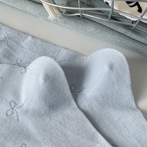 Detail of light blue ribbed socks featuring bow-tie jacquard patterns and seamless heels