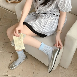 Detail of light blue mesh socks with diamond patterns and ruffle cuffs on a model