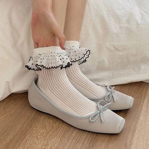 Détail de chaussettes à volants blanches avec pois noirs et bordure en dentelle douce