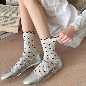 Detail of white heart-patterned socks with black wavy ruffles and silver shoes