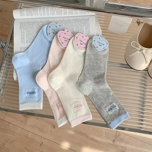 Close-up of four colors of ribbed lace mid-calf socks displayed on an open book