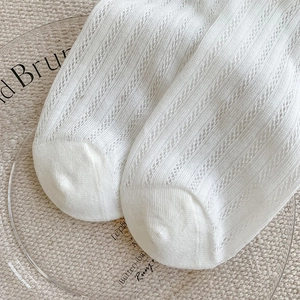 Detailed macro view of white hollow-out mesh knit socks with wave patterns and breathable texture