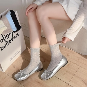 Detail of grey diamond-pattern mesh socks paired with silver metallic ballet flats