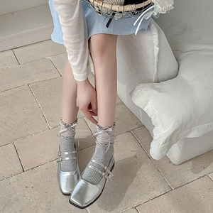 Detail of grey mesh socks with delicate frilled edges and elegant ribbon bows on feet