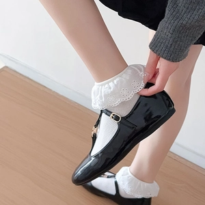 Detail of white lace socks with embroidery paired with black patent leather Mary Jane shoes