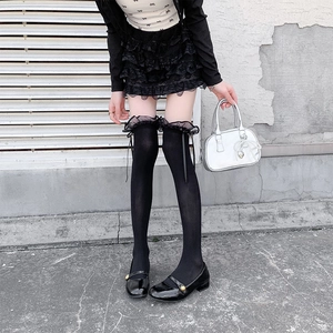 Detail of black over-knee socks with lace trim and delicate ribbon bows on the top