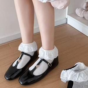 Detail of white lace socks with floral patterns paired with black Mary Jane T-strap shoes