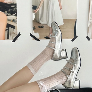 Dettaglio di scarpe Mary Jane argento metallizzato con cinturini e calze di pizzo