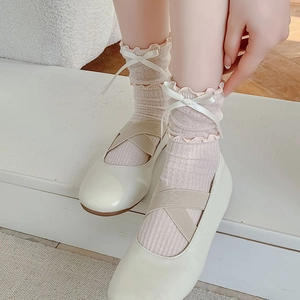 Detail of pink mesh socks with ribbon bows and ruffled edges worn with Mary Jane shoes