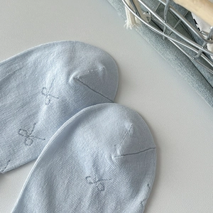 Close-up of light blue cotton socks with delicate butterfly embroidery and knit texture