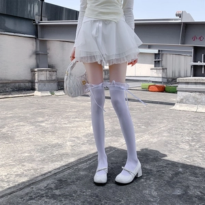 Detail of white lace over-the-knee socks with delicate silk bow and ruffle trim accents