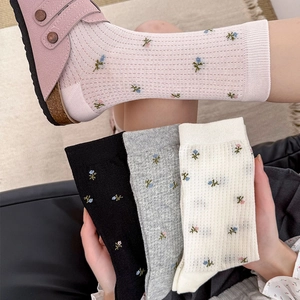 Détail de chaussettes à fleurs avec texture côtelée en rose, noir, gris et blanc