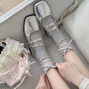 Close-up of grey knit ballet style socks with ruffled edges and ribbon bow details