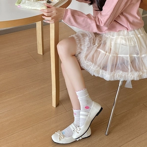 Close-up of white Mary Jane shoes with bows and mesh polka dot ruffle socks