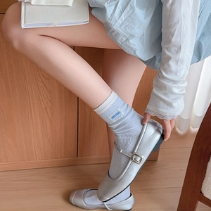 Close-up of silver Mary Jane shoes with blue and white striped lace crew socks