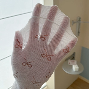Detailed view of white sheer mesh socks featuring embroidered red bow patterns