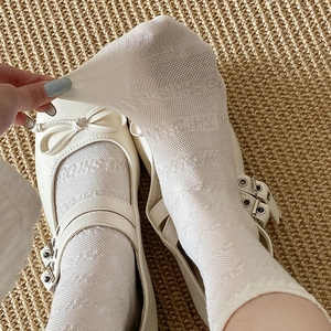 Détail de chaussettes en dentelle blanche avec chaussures Mary Jane à nœuds délicats