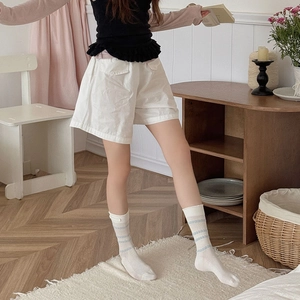 Styling of sweet white lace socks with blue stripes and high-waisted shorts in home setting