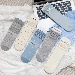Detail of light blue and grey hollow lace socks with bow ties and ribbon accents