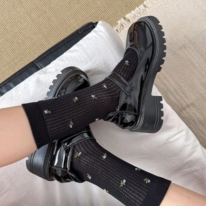 Broderie détaillée de fleurs colorées sur des chaussettes noires à côtes et chaussures Mary Jane