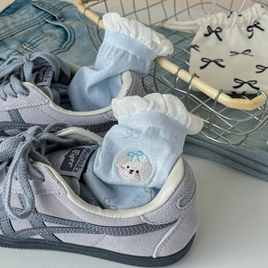 Detail of light blue ruffle socks with dog embroidery tucked into stylish sneakers