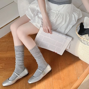 Detailed view of silver Mary Jane flats paired with grey slouchy knit cotton socks