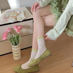 Close-up of heart patterned lace crew socks with green trim and matching bow shoes