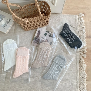 Flat lay of five pairs of ruffled mesh crew socks in assorted colors with packaging