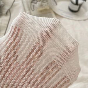 Détail du tissu en maille blanche montrant la structure respirante et élastique du bas