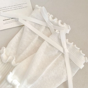 Detailed macro view of white lace mesh socks with ribbon bows and ruffled edges