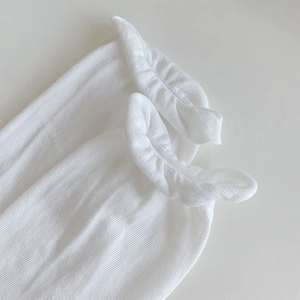 Close-up of white vertical ribbed knit socks with elegant ruffled edge design