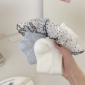 Détails de chaussettes en dentelle bleue et blanche à pois noirs et texture en maille côtelée