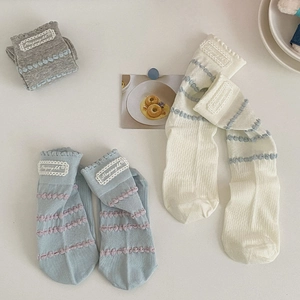 Detailed close-up of lace edge ruffles and raised dot textures on three-color knit socks