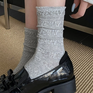 Détail de chaussettes grises à volants texturés avec mocassins noirs vernis