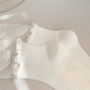 Detailed macro view of cream ballet ribbon socks featuring knit mesh and ruffled cuffs