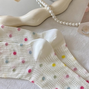 Detail of white mesh socks featuring colorful polka dots and hollow heart textures