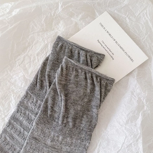 Close-up of grey textured knit socks with ribbed vertical pattern and rolled cuff