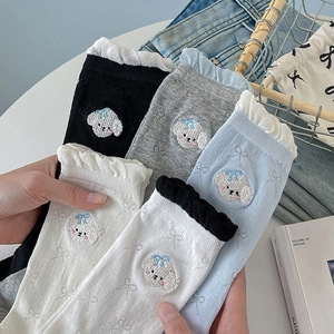 Detail showing five pairs of socks with cute dog embroidery and lace trim on cotton fabric