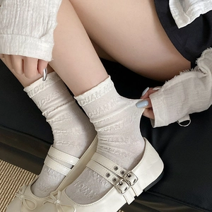 Gros plan de chaussettes en dentelle blanche et de chaussures Mary Jane avec des nœuds
