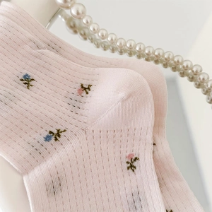 Gros plan de chaussettes rose clair avec broderie florale et texture en maille respirante