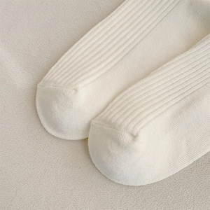 Close-up of white ballet style ribbed socks showing fine vertical knit texture and soft cotton