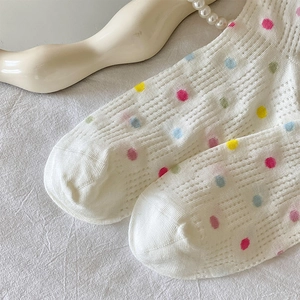 Close-up of white breathable mesh socks with colorful polka dots and ruffled edges