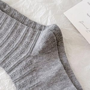 Detail of grey knitted mid-calf socks with vertical hollow stripes and reinforced heel