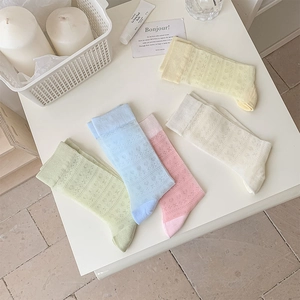 Flat lay of five pairs of macaron-colored mesh socks with floral heart pointelle patterns