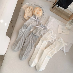 Detail of ballet style mesh socks featuring silk ribbon bows and ruffled lettuce edges