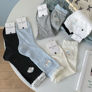 Flat lay of colorful mid-calf socks with puppy embroidery and sweet ruffle lace edges